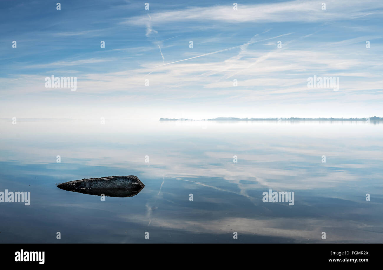 Einen Felsen auf eigene im Strangford Lough mit schönen Reflexionen der Wolken an einem blauen Himmel. Stockfoto