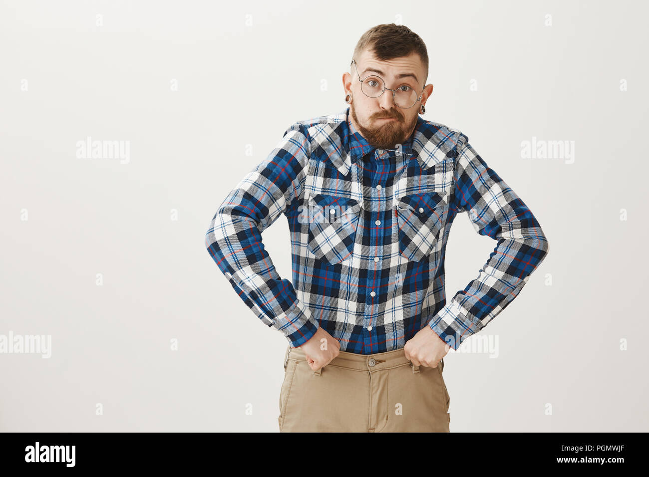 Kerl erhielt Alten zu schnell. Lustige begabten männlichen Schauspieler in Gläsern und Blue Plaid Shirt nachahmen, Großvater, Gesichter machen und mit geballten Fäusten in der Nähe der Hüfte in Urkomischen darstellen, stehen über graue Wand Stockfoto