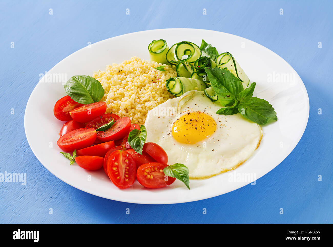 Gesundes Frühstück. Diätetisches Menü. Millet Porridge und Tomaten, Gurken Salat und gebratene Eier. Stockfoto