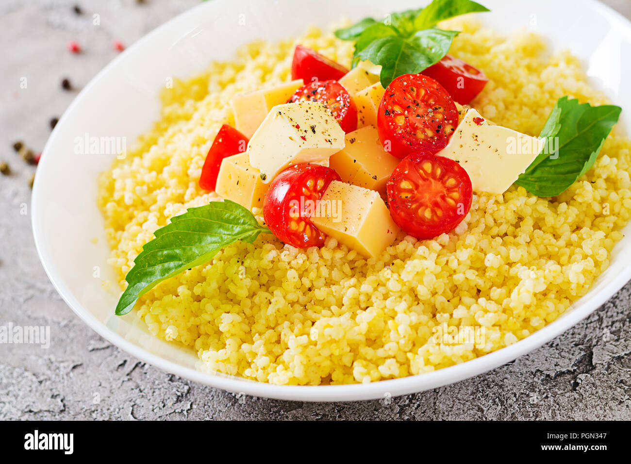 Millet Porridge mit Käse, Butter und Basilikum in weiße Schüssel. Leckeres Essen. Frühstück. Stockfoto