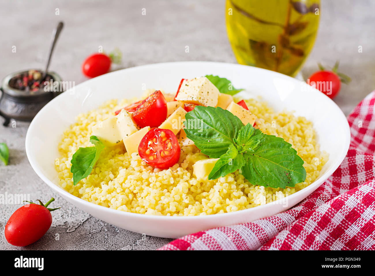Millet Porridge mit Käse, Butter und Basilikum in weiße Schüssel. Leckeres Essen. Frühstück. Stockfoto