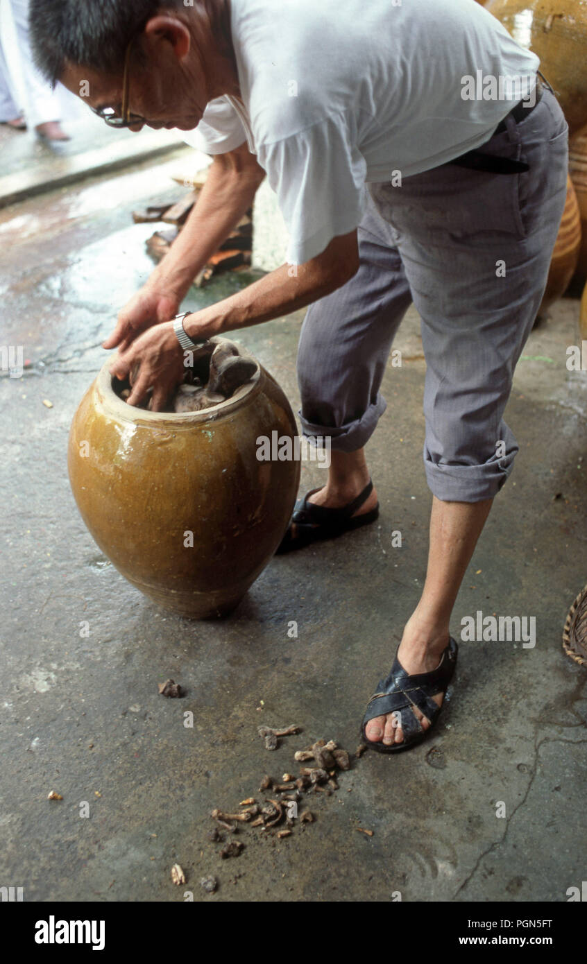 Ein Mann entfernt Knochen aus Steingut Steingut jar und wäscht sie in einem ahnenkult Ritual jährlich in einigen Teilen von China durchgeführt Stockfoto