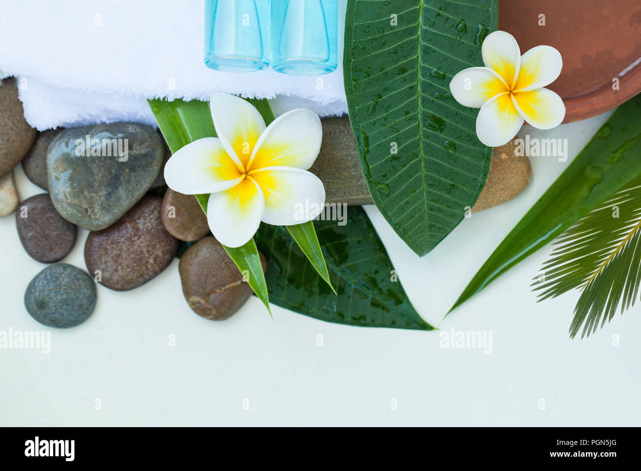 Spa, Wellness oder Hintergrund mit weißer Bettwäsche, tropische Blätter, Blumen, Körper und Gesicht pflege Werkzeuge und Zubehör auf weißem Hintergrund, Ansicht von oben. Stockfoto