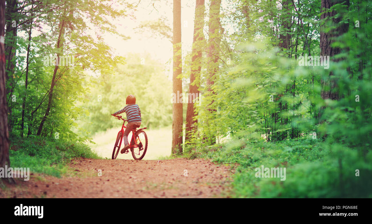 Kind auf dem Fahrrad in den Wald am frühen Morgen Stockfoto