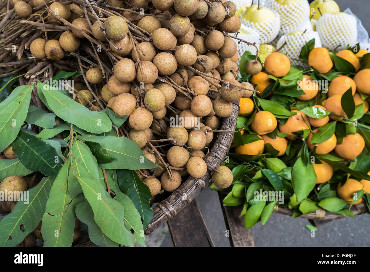 Verschiedene Arten von Früchten, die aus den traditionellen Hängekörben verkauft werden, finden sich in Hanoi, Vietnam. Stockfoto