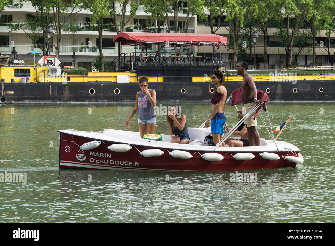 Fünf Freunde genießen die elektrische Bootsfahrt entlang der Ourcq Canal in Paris, Frankreich. Stockfoto