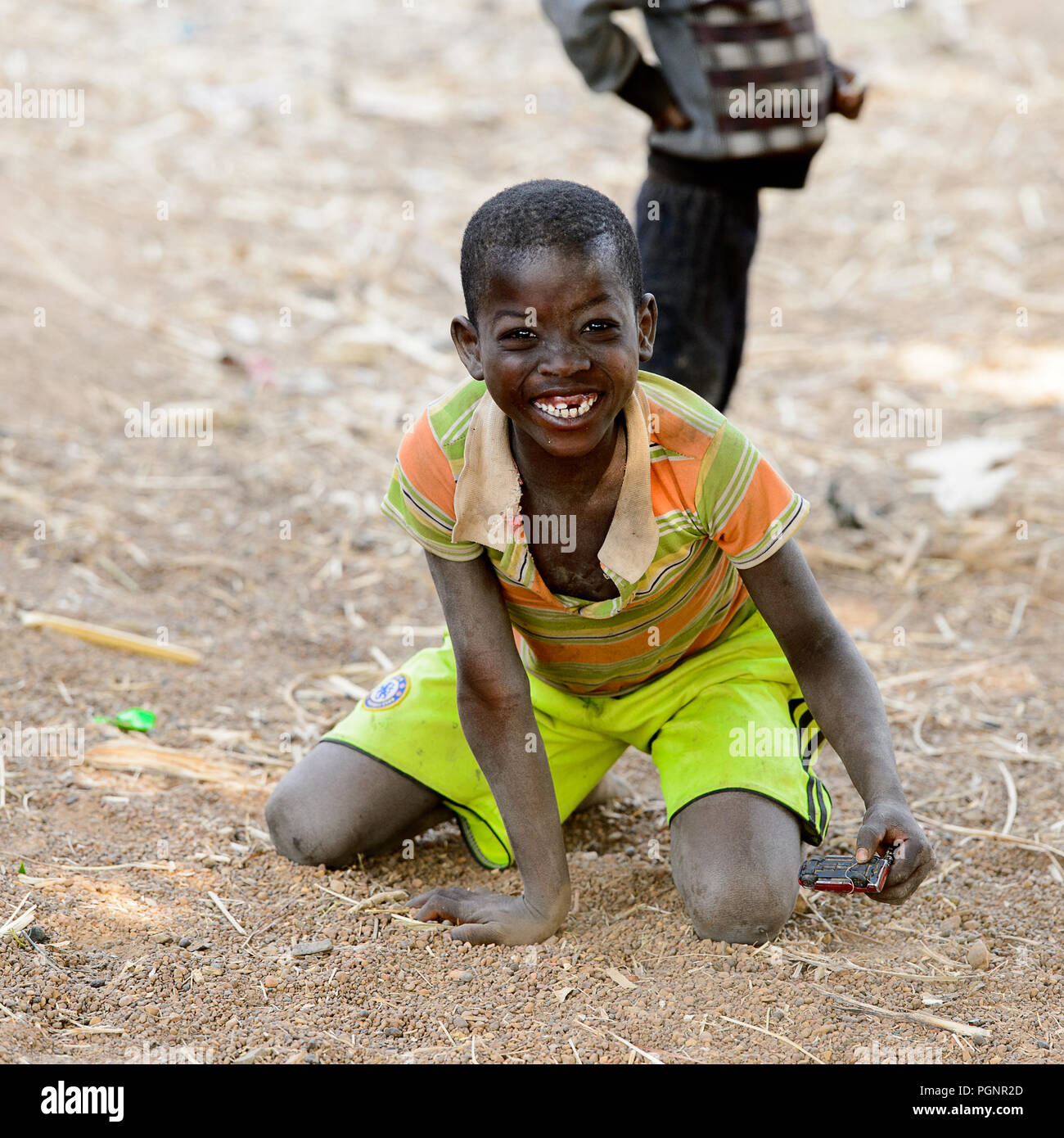 GHANI, GHANA - Jan 14, 2017: Unbekannter ghanaischen Junge im gestreiften  Kleidung sitzt auf dem Boden in der ghani Dorf. Ghana Kinder leiden der  Armut du Stockfotografie - Alamy