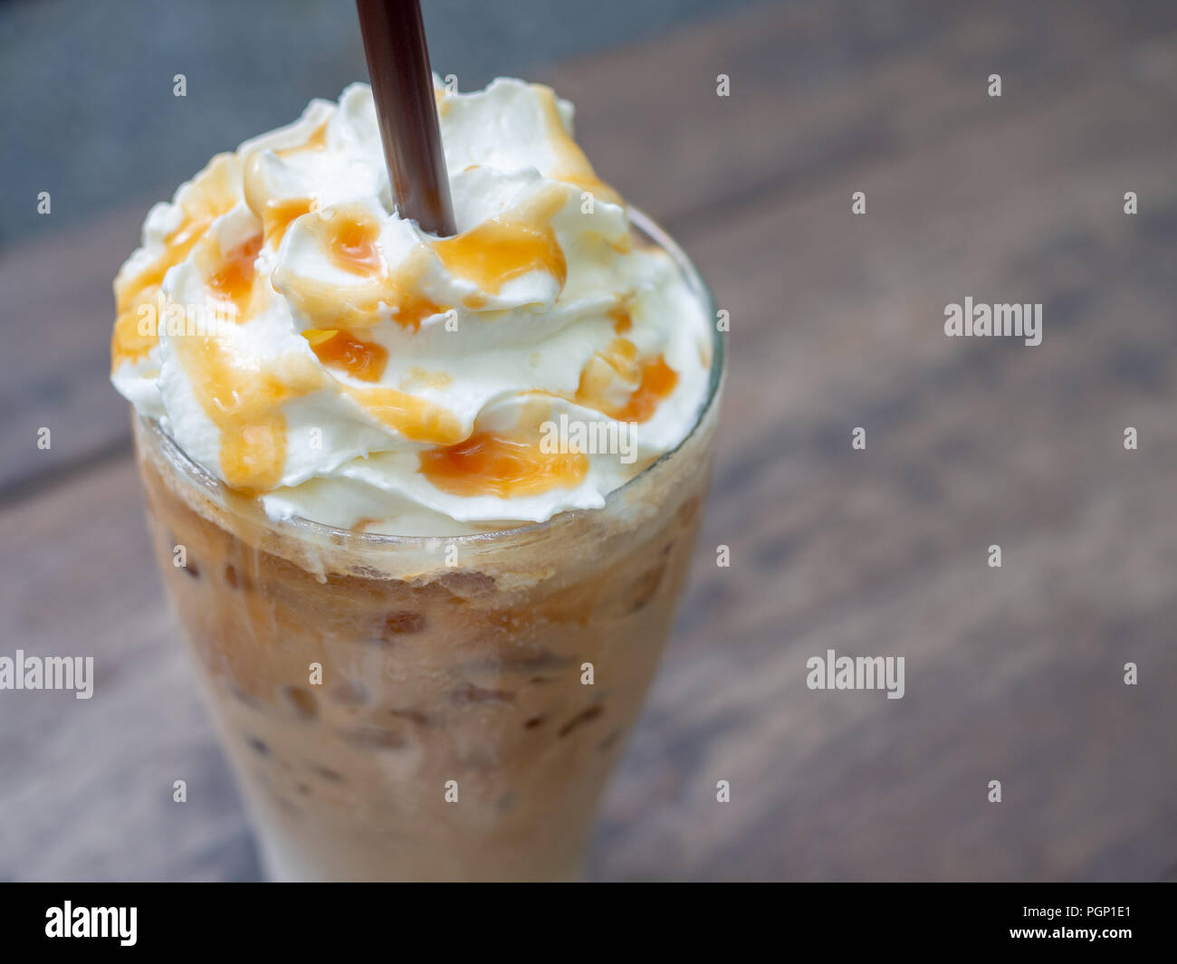 Close-up Iced Caramel Macchiato mit braunen Stroh im großen Glas. Kalter Kaffee trinken Frappe (frappuccino) mit Sahne und Karamell Sirup und br Stockfoto