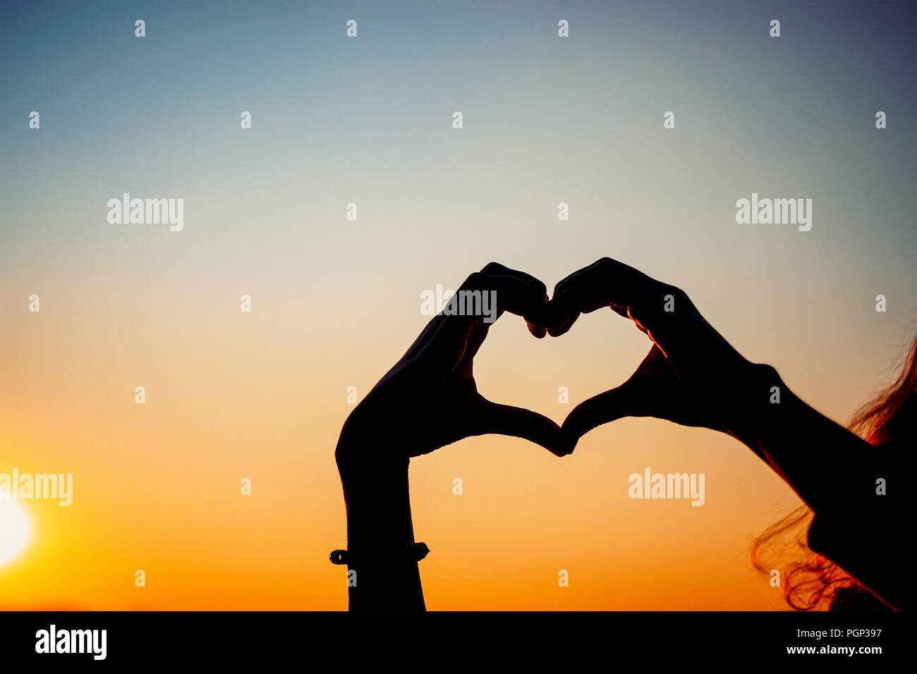 Silhouette frau Hände bilden Herzform mit Sonnenuntergang Stockfoto