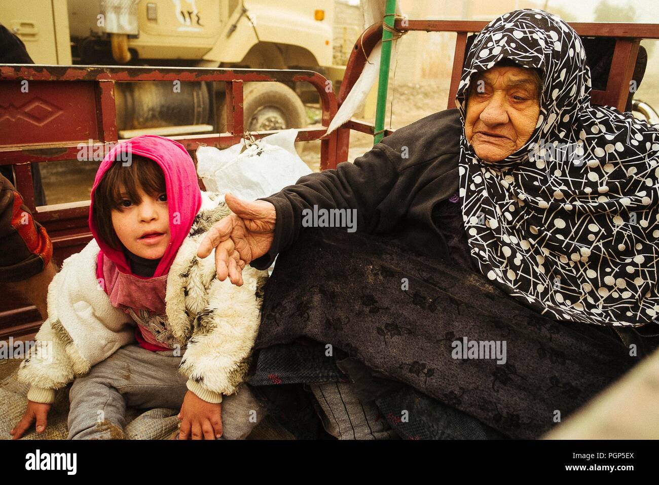 Eine Großmutter und ihre kleine granddaugher Flucht aus Mossul in die Offensive der anti-ISIS Koalition, hinter einen Pick-up. Gagjali (IQ) 2016/Dec/02 Stockfoto