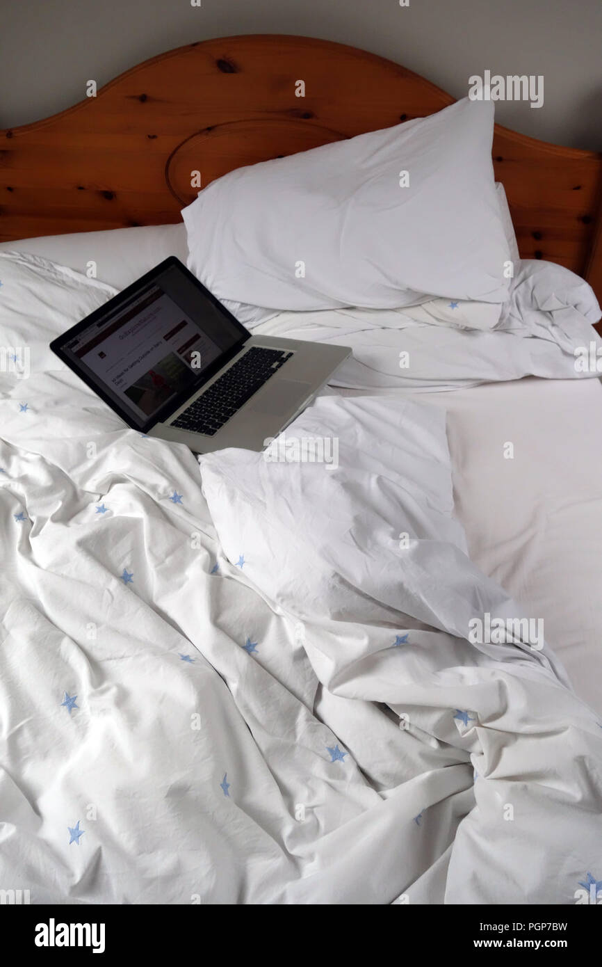 Im Bett mit frischer Bettwäsche Bettwaren und Laptop Geschlafen links oben. Eigenschaft freigegeben Stockfoto