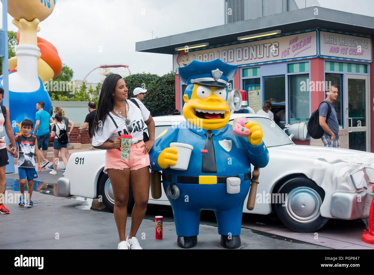 Frau, die neben einer Abbildung von Chief Wiggum in der Nähe der Simpsons Ride an der Springfield USA, Universal Studios Florida - Orlando, Florida, USA Stockfoto