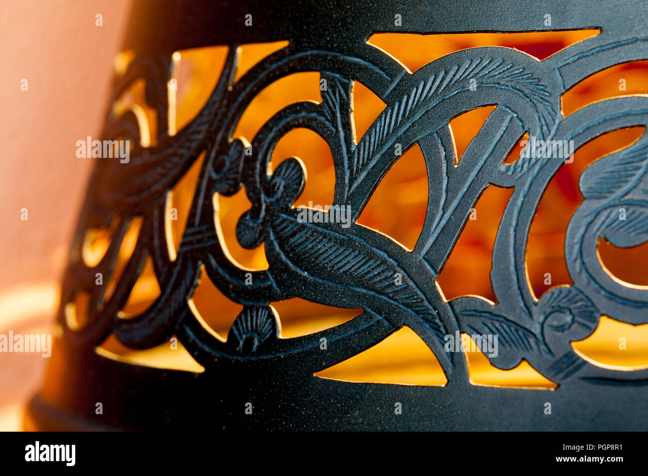 Marokkanische Black Metal cutwork Lampenschirm in Schwarz. Close up Details der wirbelnden Floral Design. Mit goldenem Licht beleuchtet. Marrakesch, Marokko Stockfoto