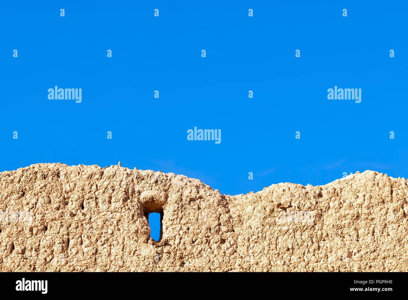 Marokko rustikalen Schlamm wand Detail mit Fenster Eröffnung gegen strahlend blauen Himmel. Kopieren Sie Platz. Stockfoto