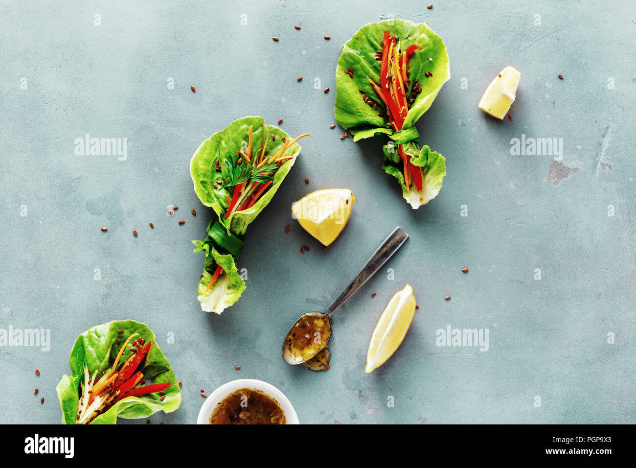 Pflanzliche Rolle mit Salatblättern romaine, Paprika, Karotte und Gurke auf blauen Stein Hintergrund. Gemüse Snacks mit Soße. Raw Food Konzept Stockfoto