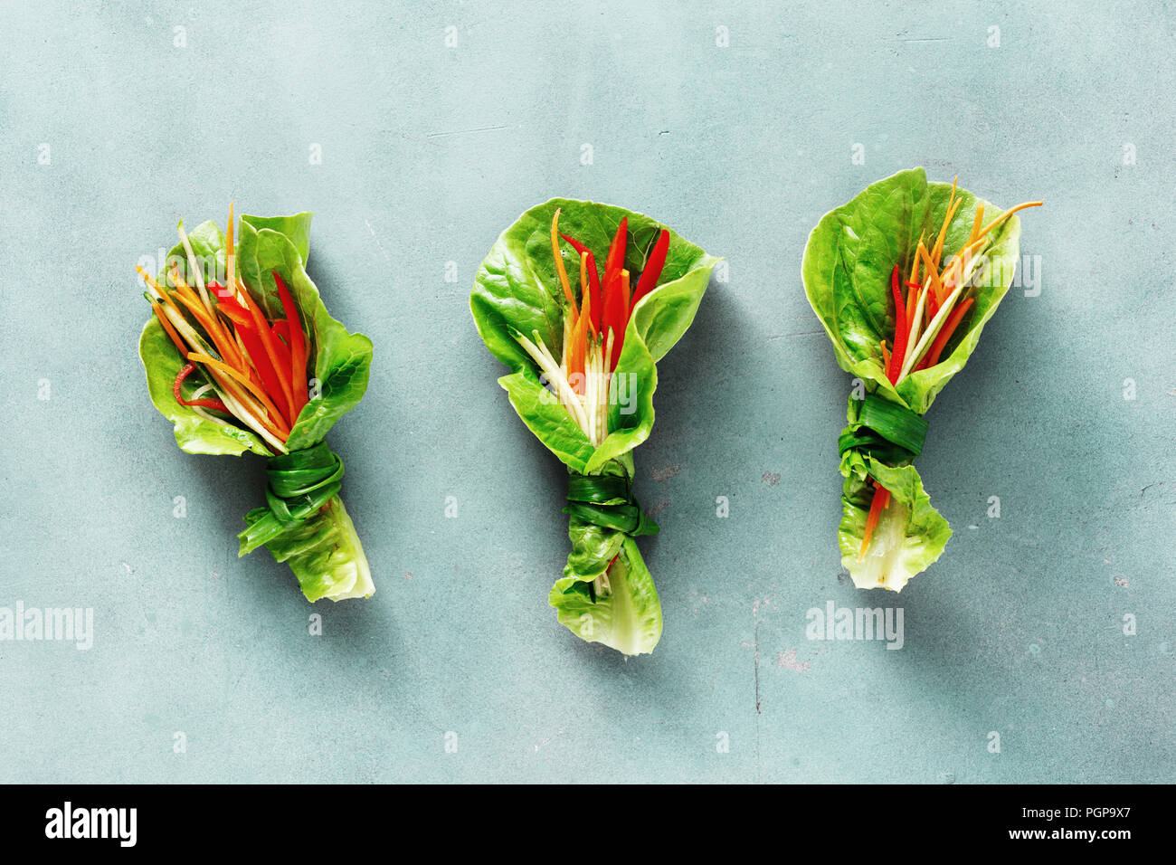 Pflanzliche Rolle mit Salatblättern romaine, Paprika, Karotte und Gurke auf blauen Stein Hintergrund. Gemüse Snacks Ansicht von oben. Raw Food Konzept Stockfoto
