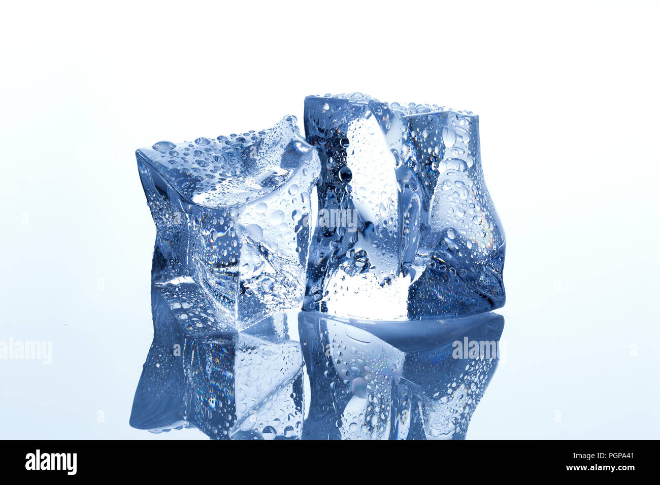 Zwei Eiswürfel mit Wassertropfen schmelzen auf weißen reflektierenden Hintergrund Stockfoto