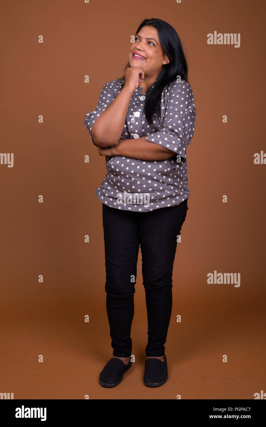 Portrait von Reifen indische Frau gegen braunen Hintergrund Stockfoto
