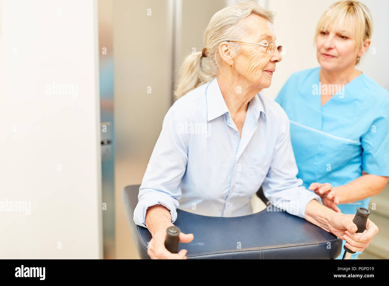 Physiotherapeut hilft eine alte behinderte Frau mit rollator an der REHA-Klinik Stockfoto