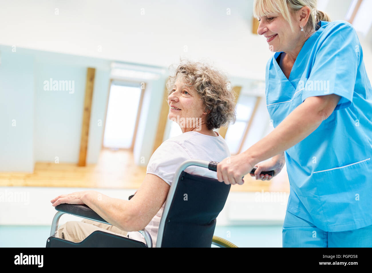 Betreuer sorgt für eine ältere Frau in einem Rollstuhl in der Physiotherapie Stockfoto