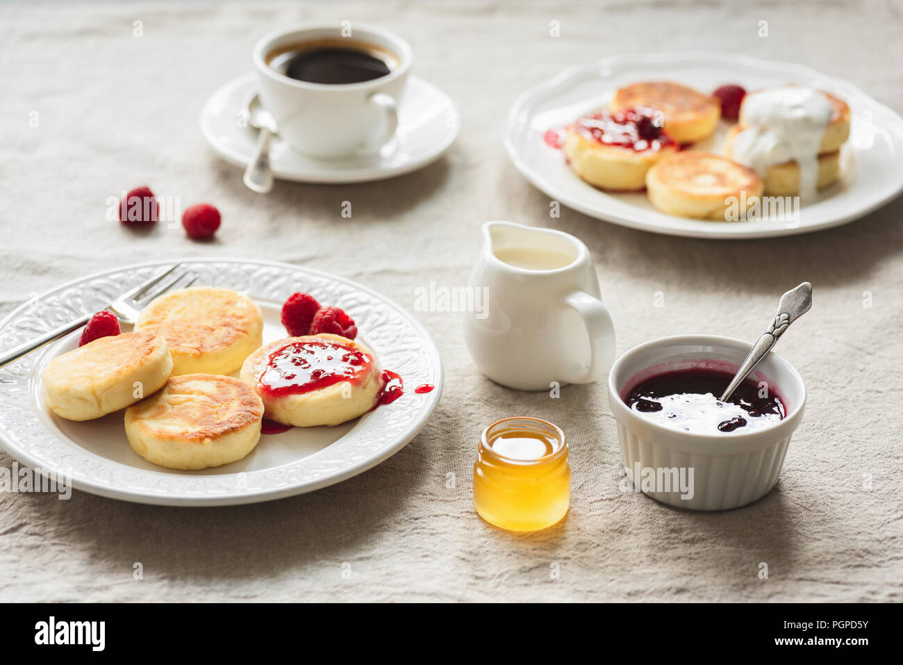Frühstückstisch mit Quark Krapfen oder Pfannkuchen, Kaffee, Marmelade und Honig. Russische, ukrainische Küche. Gemütliches Frühstück oder comfort food Konzept Stockfoto