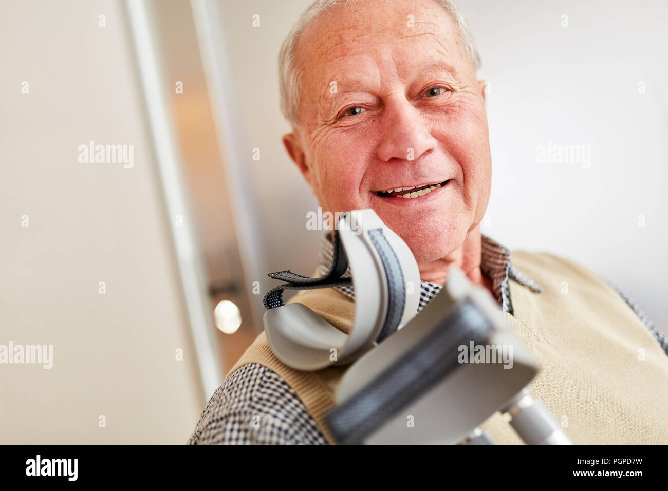 Lächelnd älterer Mann mit Krücken in der Reha Klinik oder Seniorenheim Stockfoto