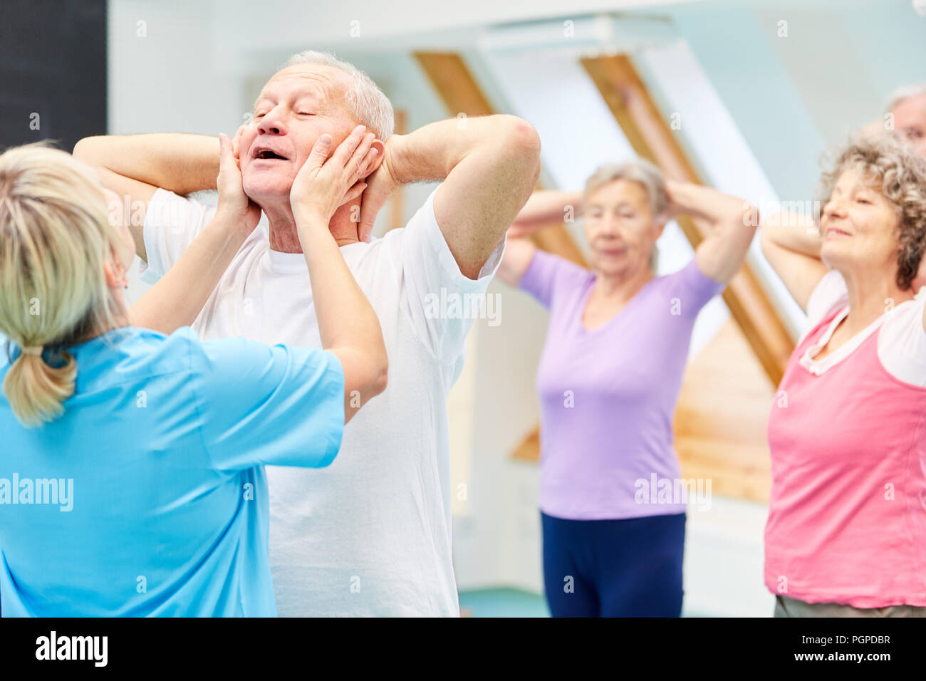 Trainer hilft Senioren mit einer Übung in einer Physiotherapie reha Kurs Stockfoto
