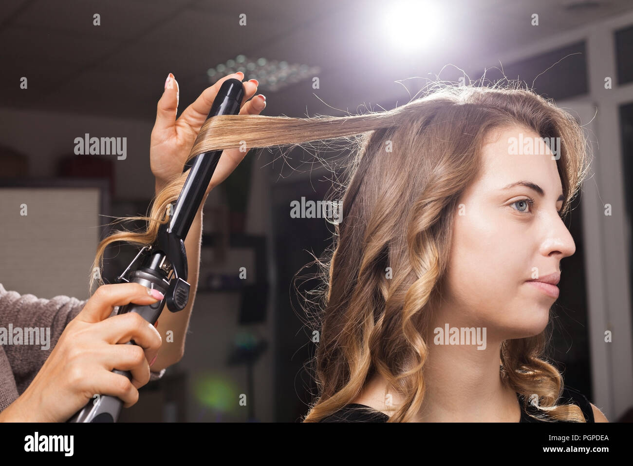 Friseur sorgfältig macht das Haar Curling an einen Client Stockfoto