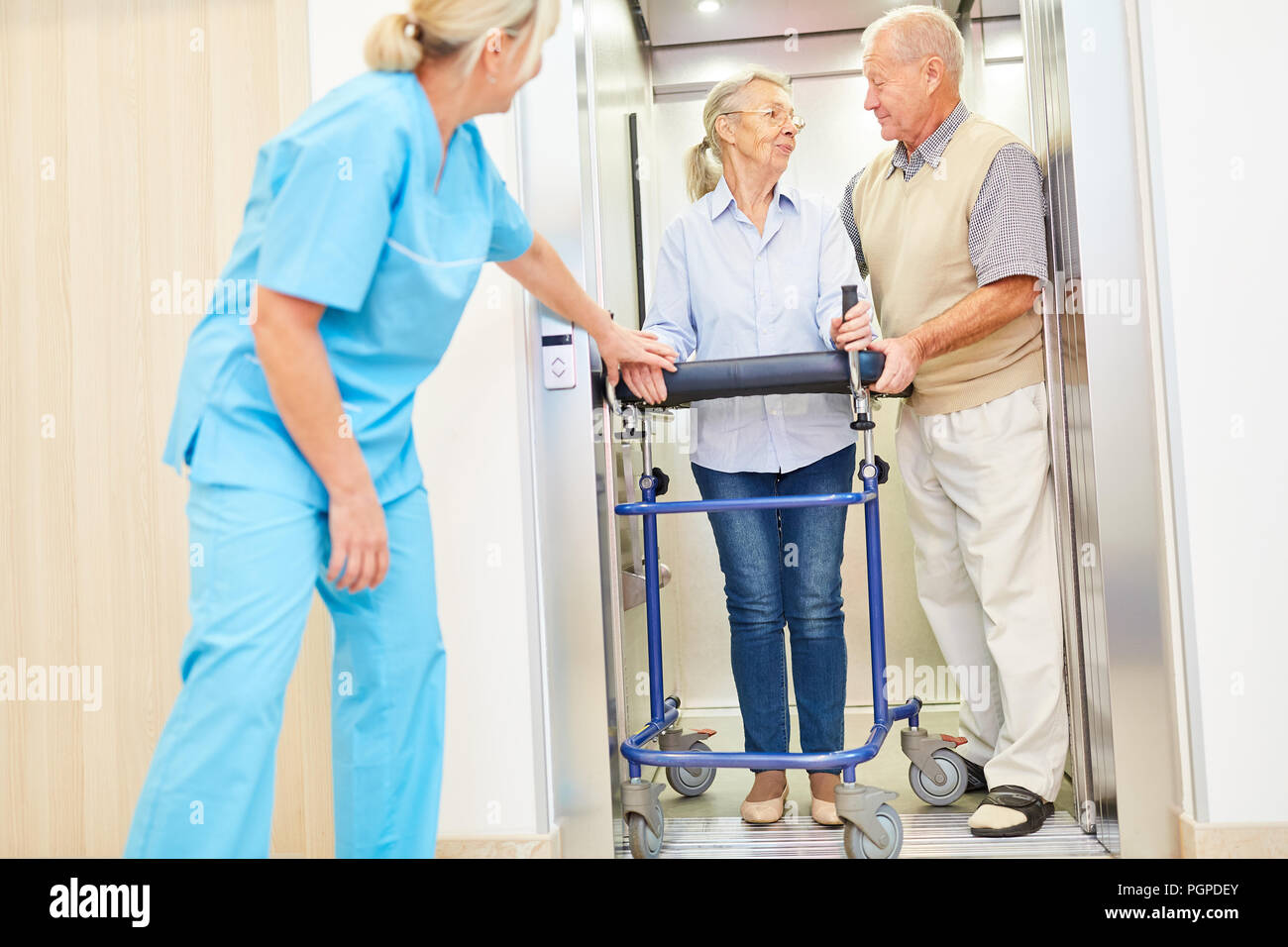 Betreuer interessiert sich für Senioren mit rollator in den Aufzug im Pflegeheim Stockfoto