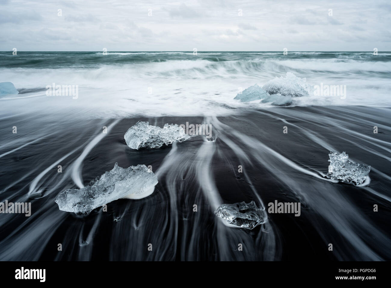 Eisige Strand in Island in der Nähe von Gletscherlagune Jokulsarlon. Eisberg auf der schwarzen vulkanischen Sand auf den Atlantischen Ozean. Touristische Attraktion. Wunderschöne Landschaft Stockfoto