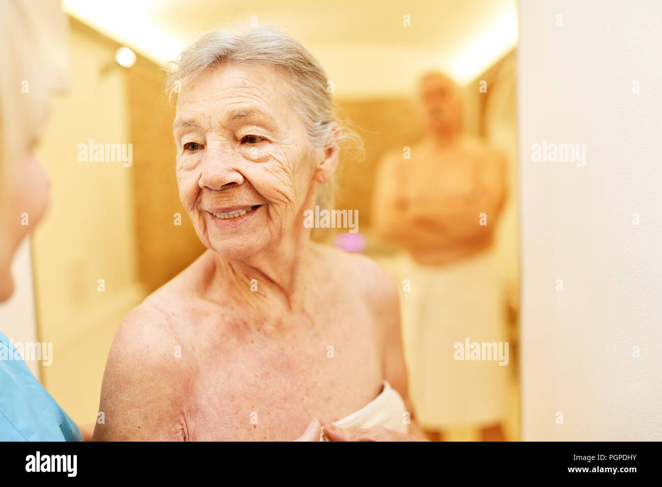 Alte Frau in der Wellness- Abteilung der Senior Residence freut sich auf die Sauna Stockfoto