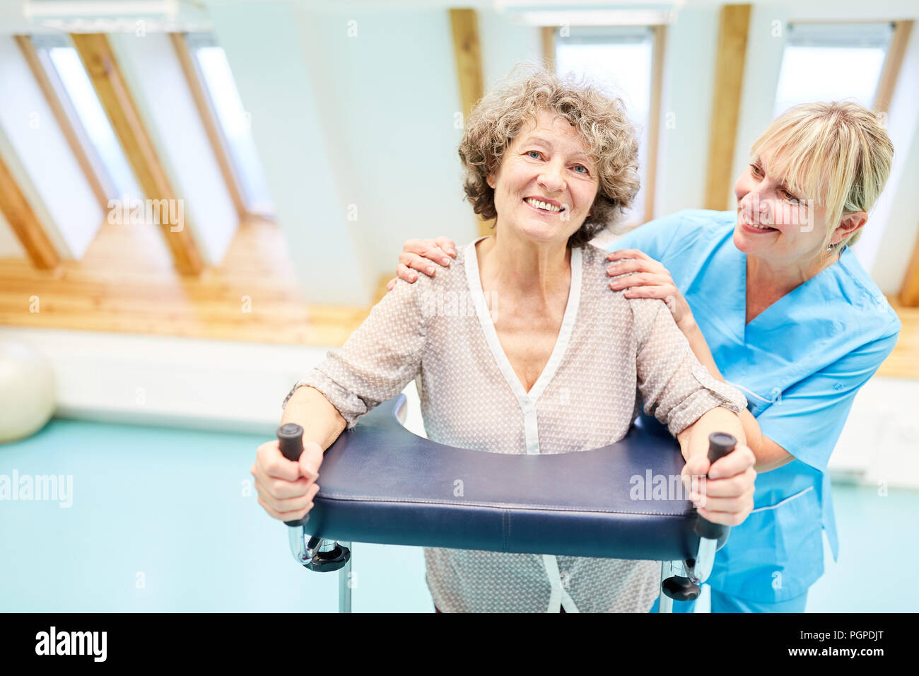 Gerne ältere Frau mit Walker und rehab therapist in der Physiotherapie Stockfoto