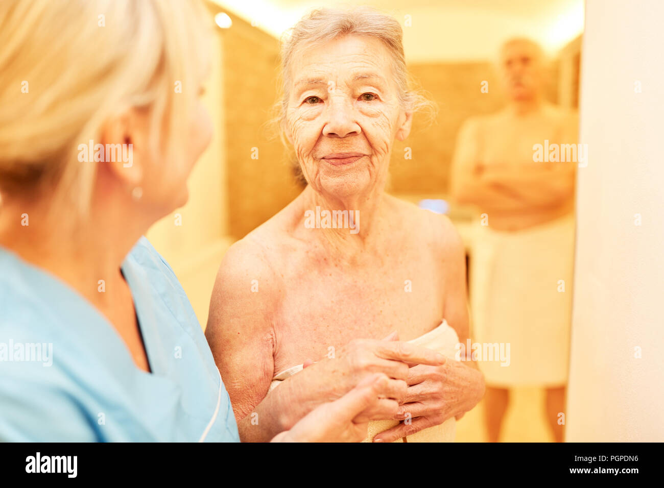 Alte Frau geht in die Sauna im Wellnessbereich des Senior Residence oder im Wellness Hotel Stockfoto