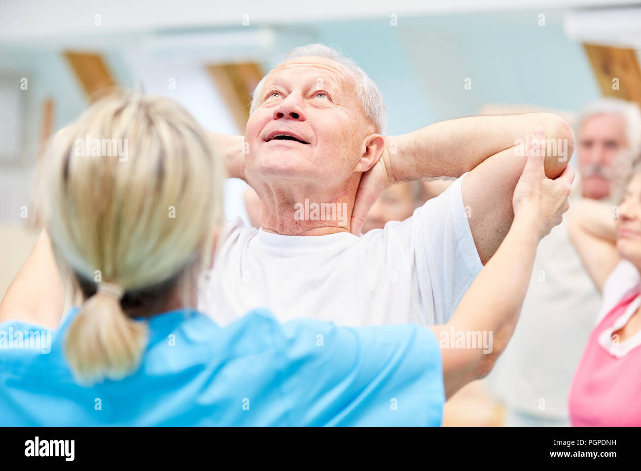 Trainer betreut älterer an der rehab Zurück Übungen in der Physiotherapie Stockfoto
