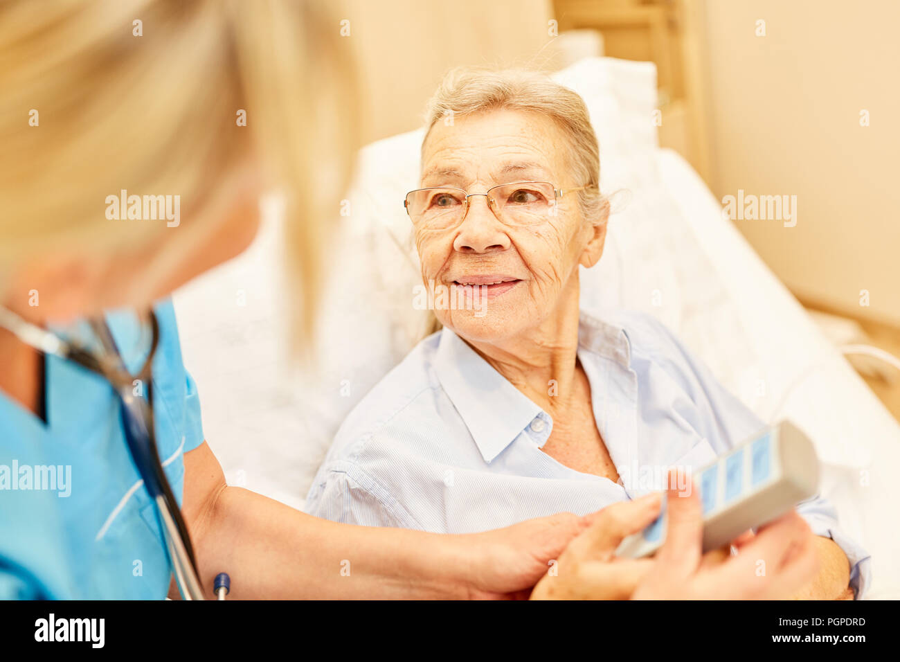 Pflegedienst sorgt für einen Bettlägerigen älteren Frau im Krankenhausbett im Pflegeheim Stockfoto