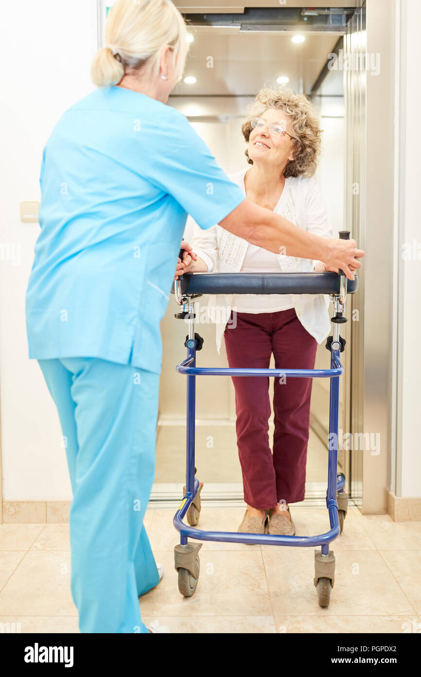 Krankenschwester hilft Senioren mit Walker beim Gehen in rehab Stockfoto