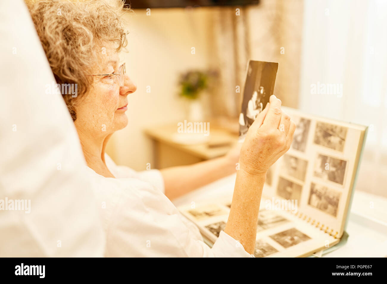 Ältere Frau sieht ein Foto aus dem Fotoalbum für Alzheimer und Demenz. Stockfoto
