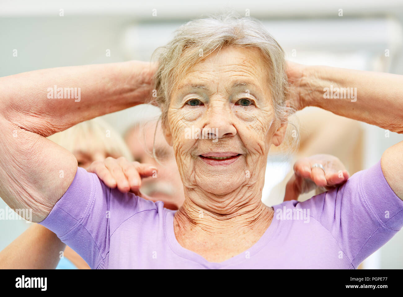 Trainer gibt einen alten Frau Hilfe bei Übungen in der Reha Stockfoto