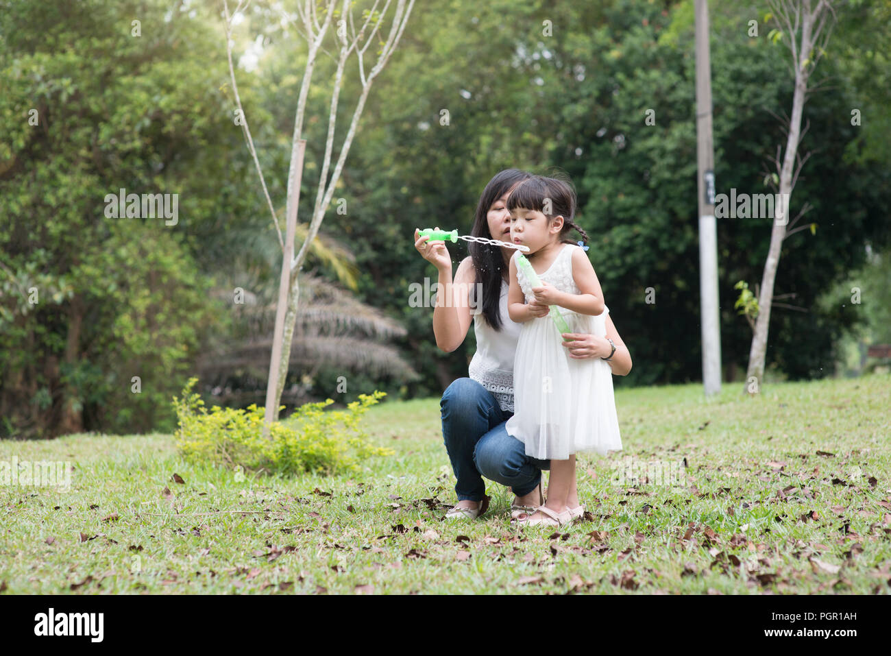 Asiatische Familie im Freien. Mutter und Tochter bläst Seifenblasen im Green Park. Stockfoto
