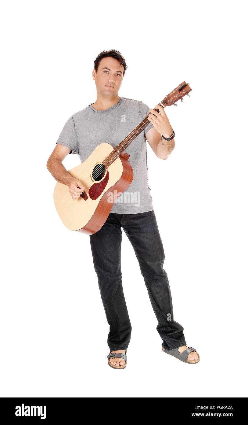 Ein junger stattlicher Mann mit seiner Gitarre und Wiedergabe eines Songs in Jeans und T-Shirt, auf weißem Hintergrund Stockfoto