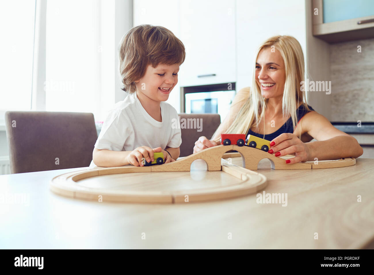 Mutter und Sohn spielen am Tisch drinnen Stockfoto