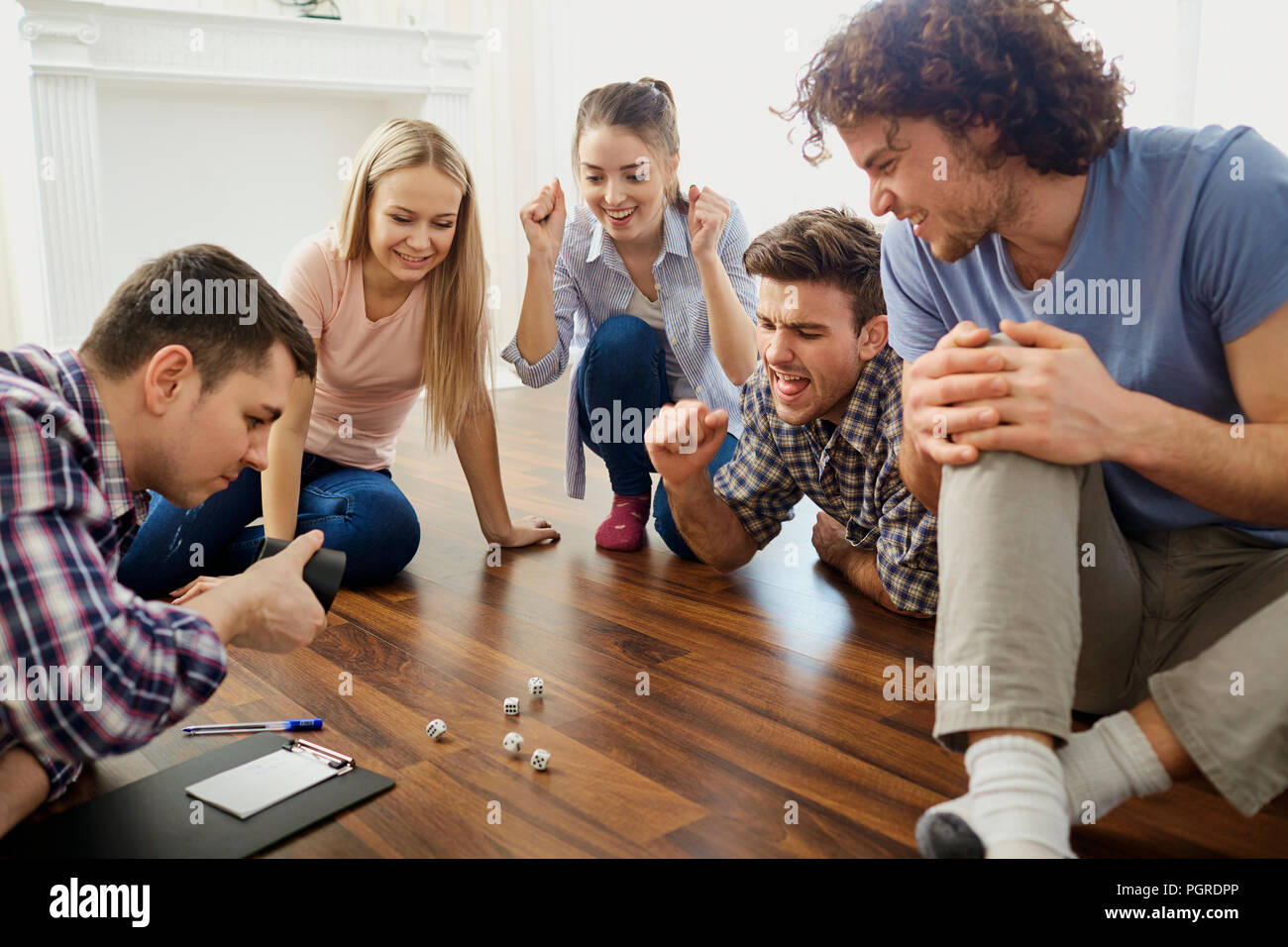 Eine Gruppe von Freunden Brettspiele spielen auf dem Boden im Innenbereich. Stockfoto
