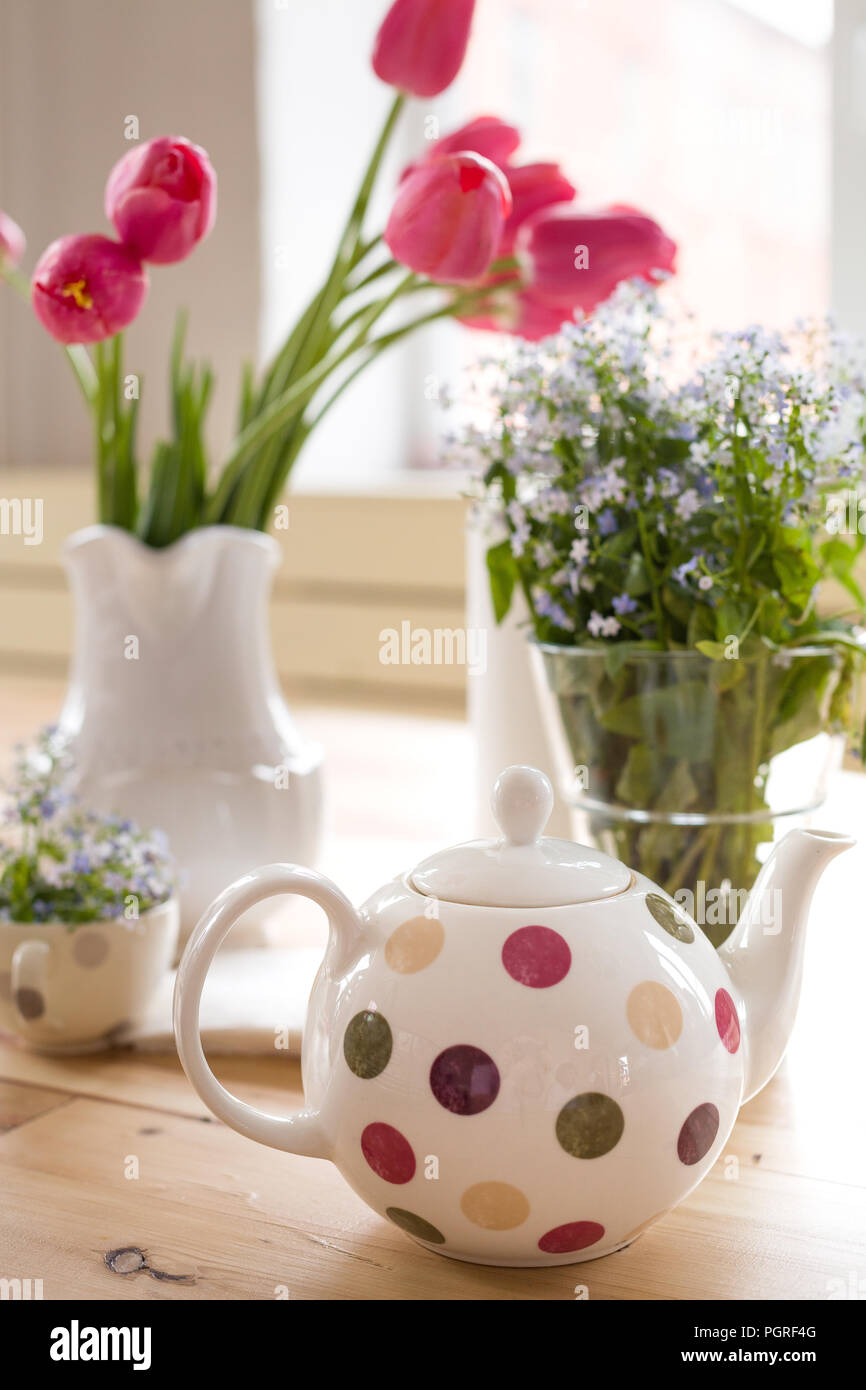 Teekanne mit Dots und Vasen mit schöner Frühling Blumen auf dem Holztisch. Dekoration für zu Hause. Forget-me-not und Tulpen in den Vasen. Blumen Stockfoto