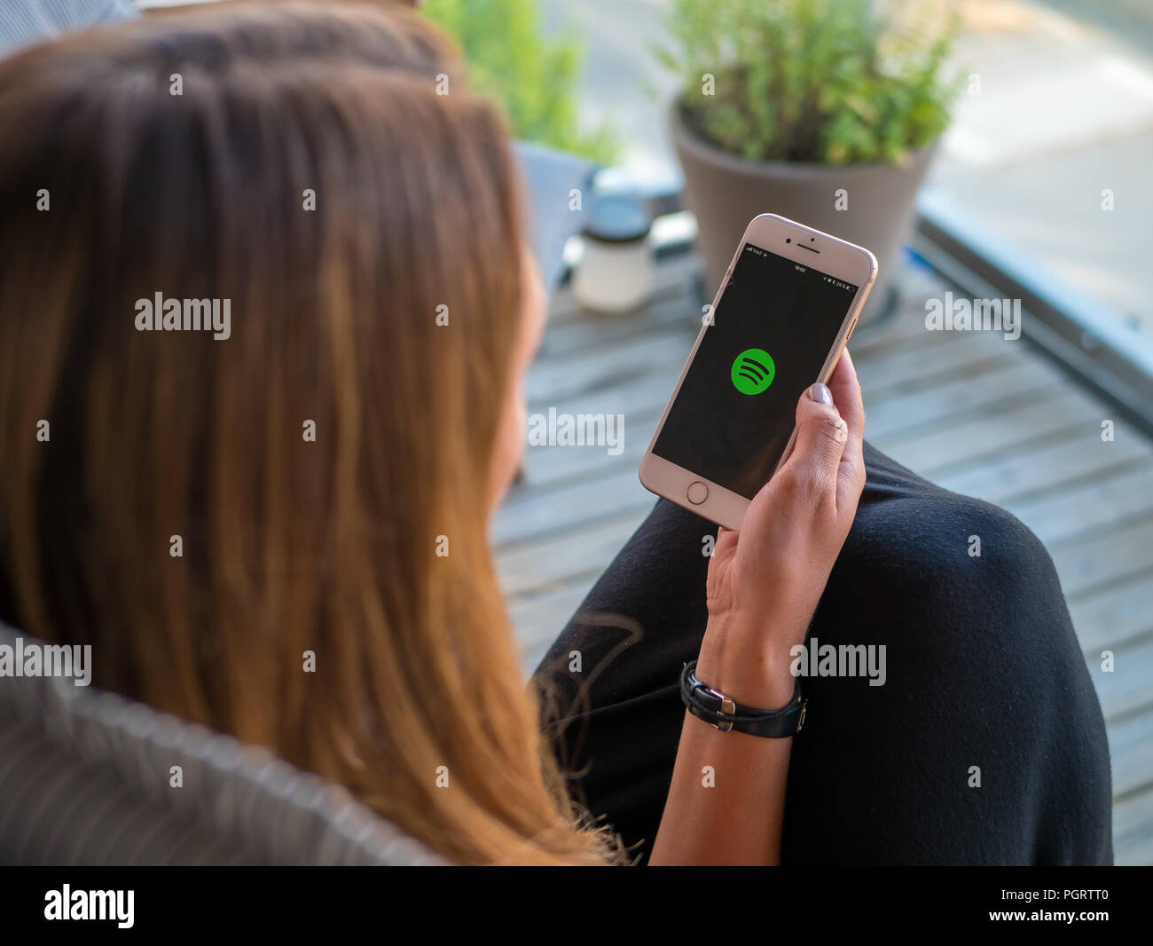 Stockholm, Schweden, 14. Juni 2018: Frauen, die ein Smartphone oder Handy mit Spotify Musik App laden. Ansicht von der Rückseite, selektive konzentrieren. Stockfoto