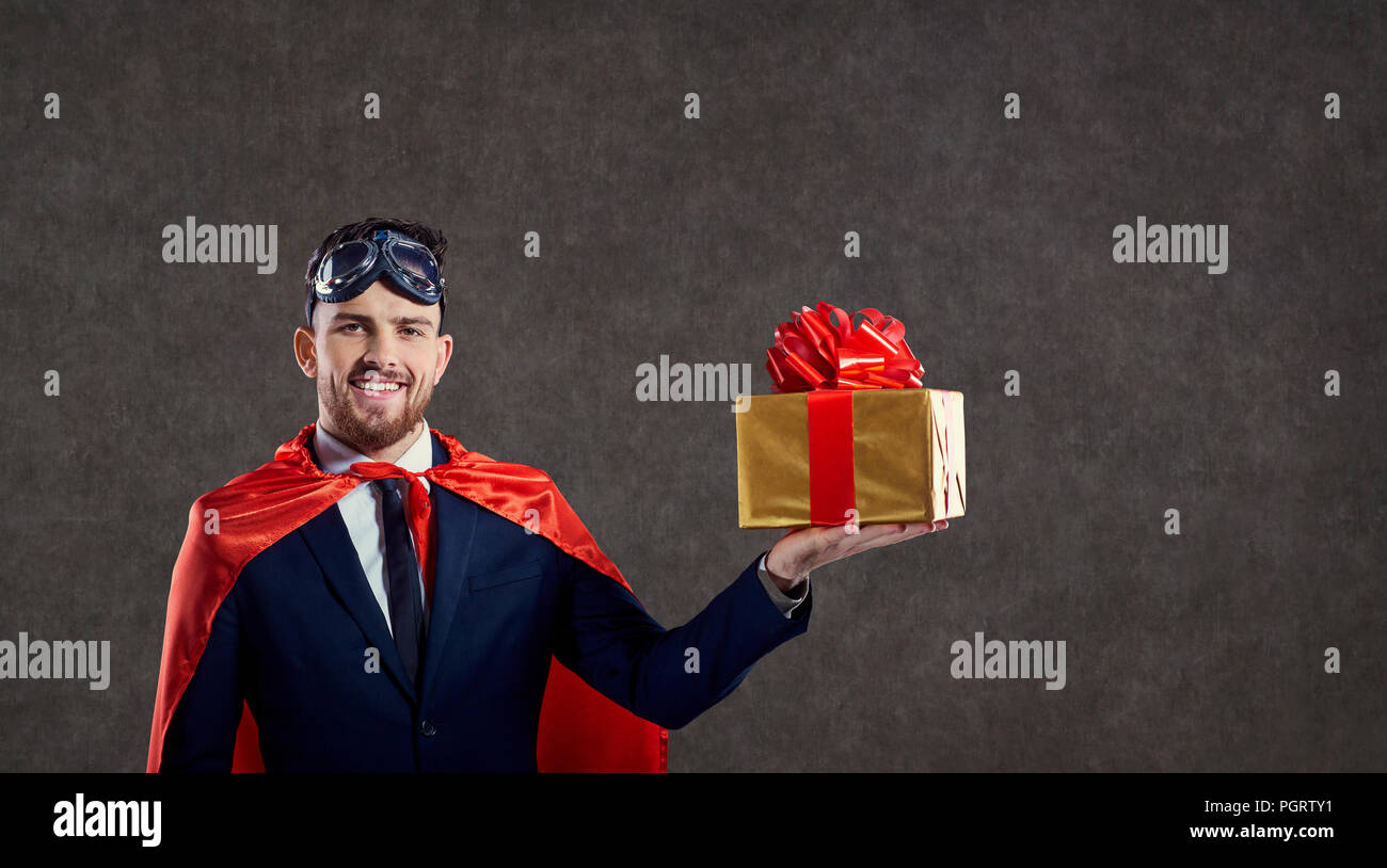 Ein Mann in einen Superhelden Kostüm mit einer Geschenkbox. Stockfoto
