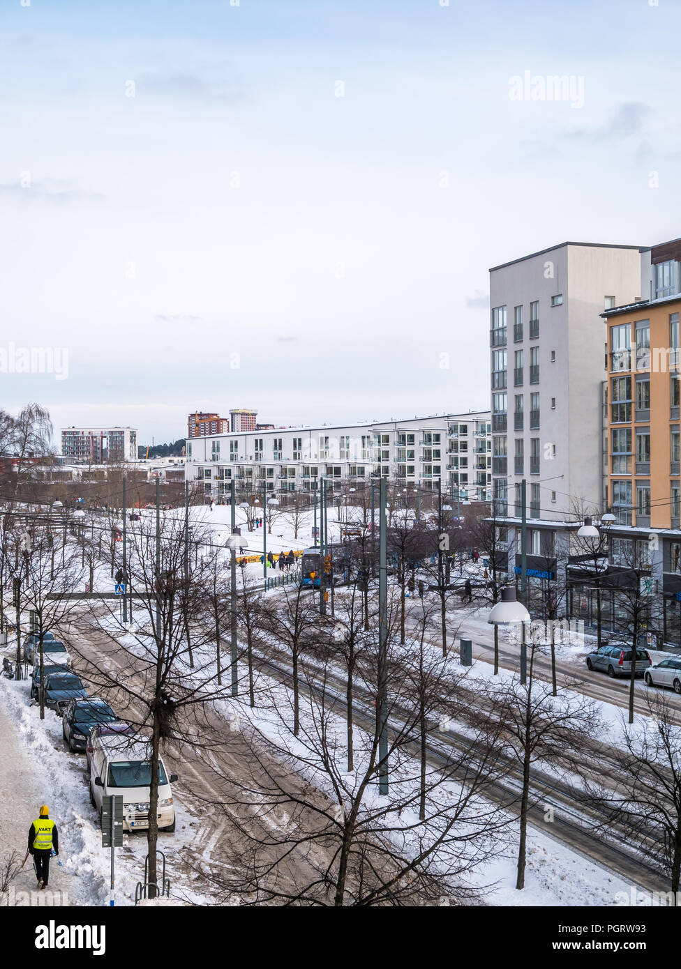 Stockholm, Schweden, 4. Mars 2018: Winter in Hammarby Sjöstad in südlich von Stockholm. Die Straßen sind mit Schnee bedeckt. Straßenbahn im Hintergrund und die Kinder spielen auf s Stockfoto