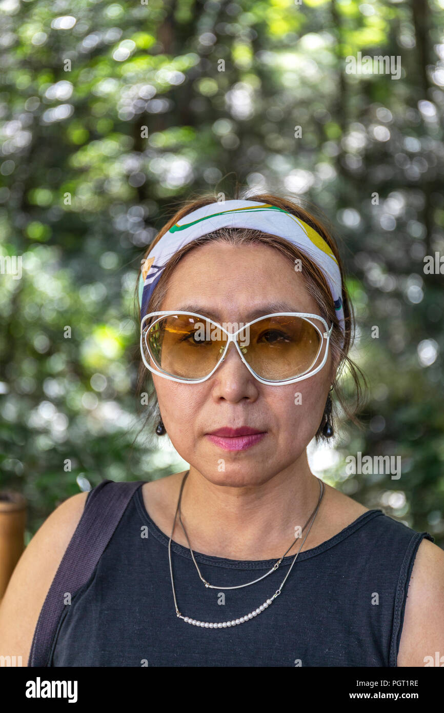Portrait von zuversichtlich und selbstbewusst in Taiwan chinesische Frau gegen den Hintergrund des unscharfen Laub. Stockfoto