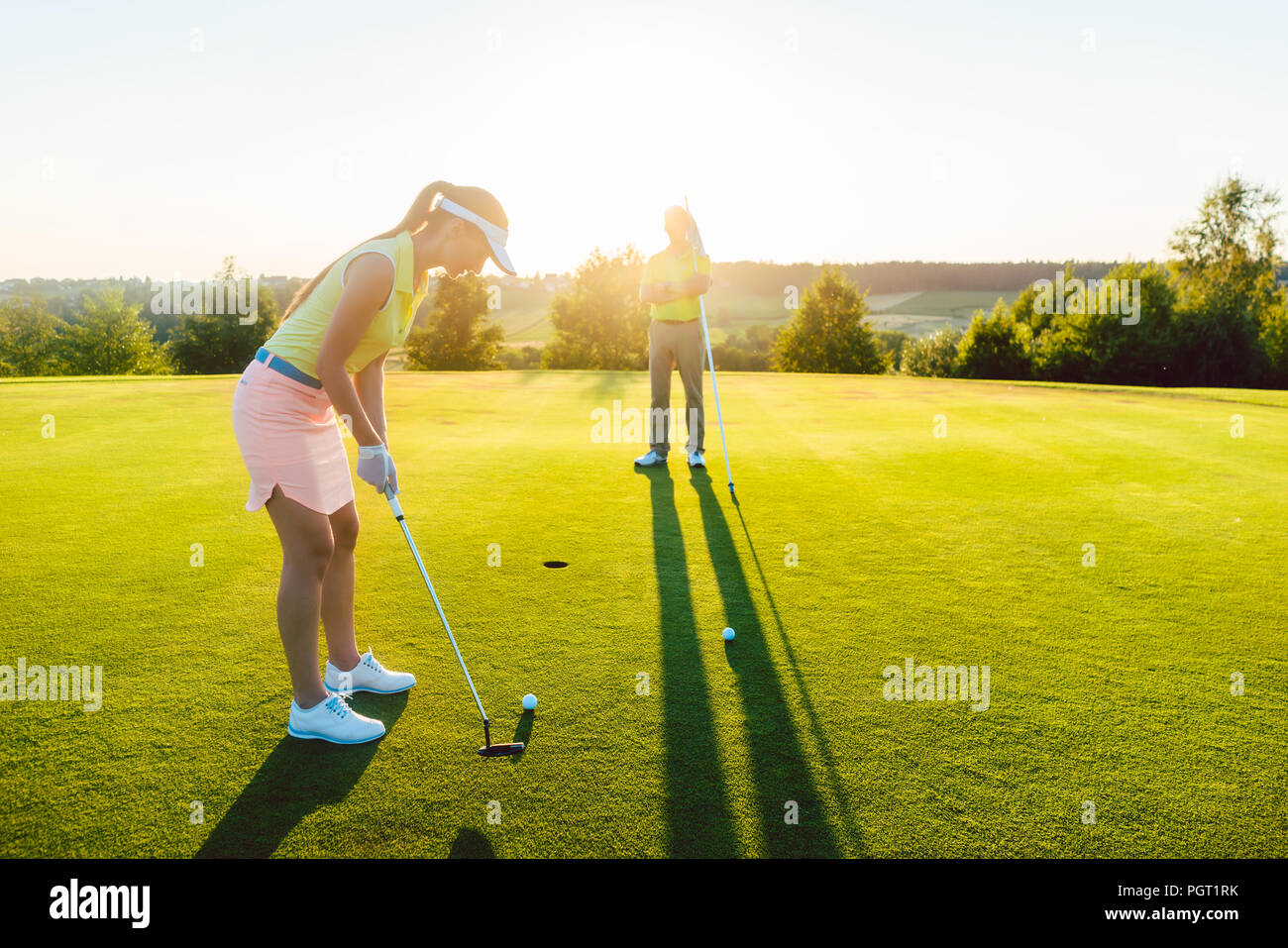 Weibliche Golf Spieler bereit, den Ball in die Schale zu schlagen Stockfoto