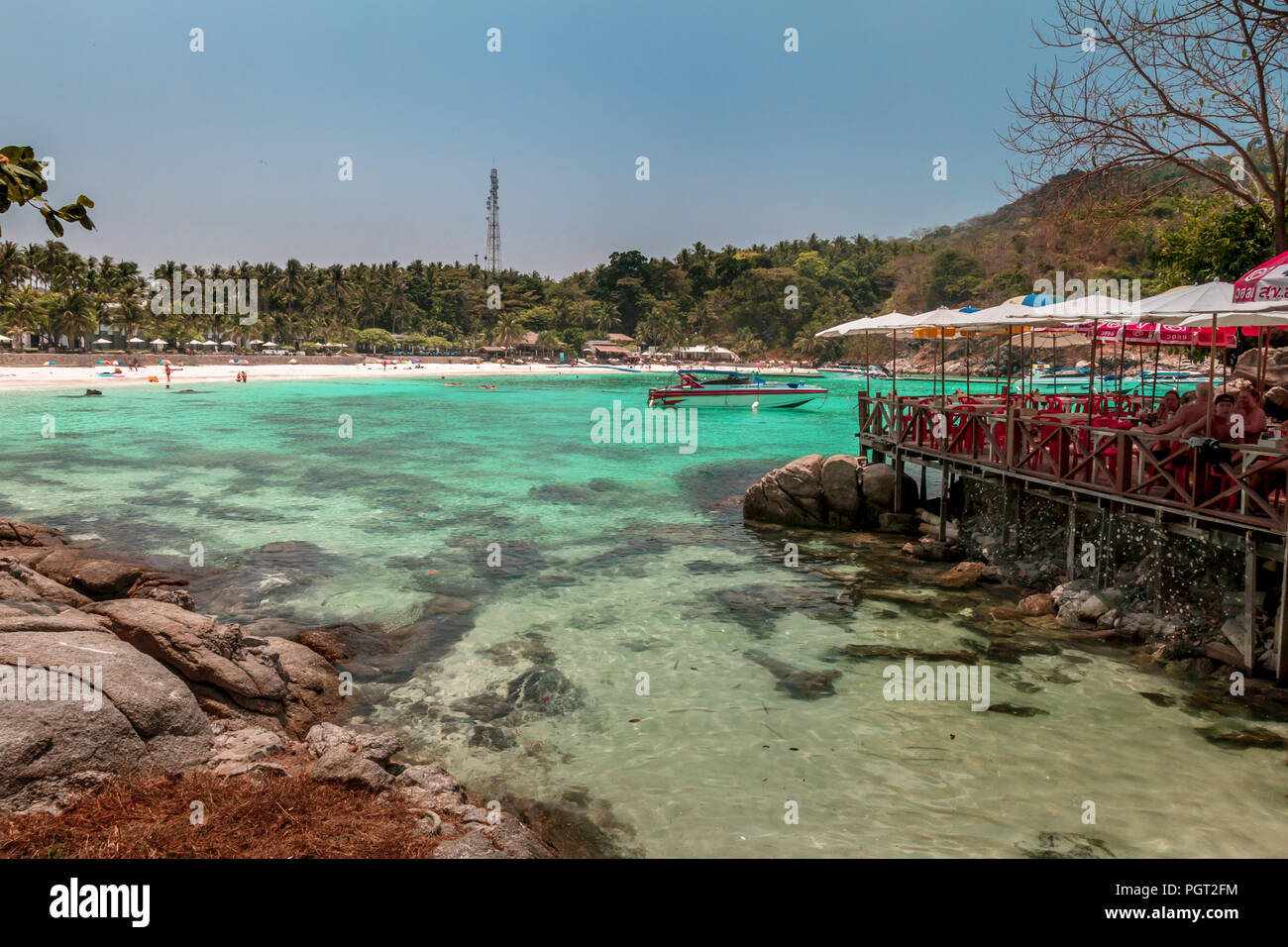 Raya Island Bay mit Sonnenschirmen und dockside Restaurant für Touristen, die zu Besuch kommen. Stockfoto