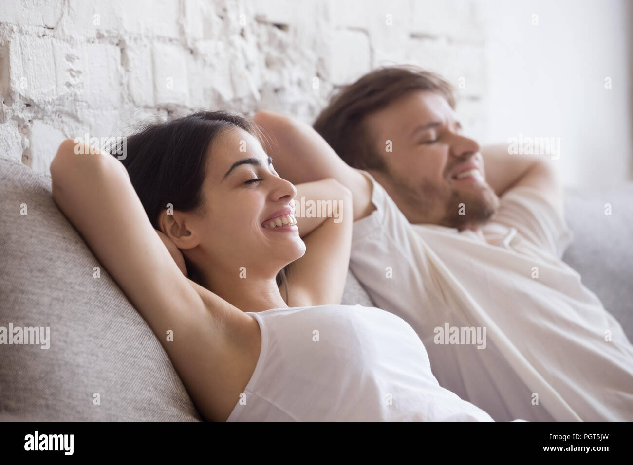 Glückliches Paar liegt entspannt auf einem Sofa mit geschlossenen Augen Stockfoto